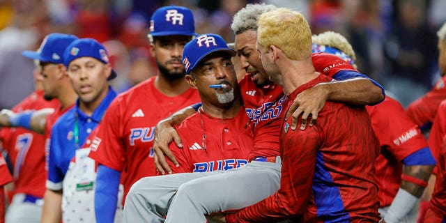 Puerto Rico pitcher Edwin Diaz, #39, gets taken off the field by pitching coach Ricky Bones, #27, after an apparent leg injury during the team victory celebration against the Dominican Republic at loanDepot park in Miami.