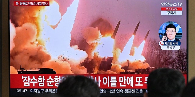 People stand near a television showing file footage of a North Korean missile test, at a railway station in Seoul, March 14, 2023.