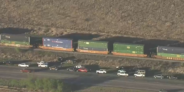 Law enforcement vehicles and officers photographed via helicopter investigating train cars where more than a dozen migrants were found suffocating near San Antonio, TX. (Credit: KENS 5 San Antonio)