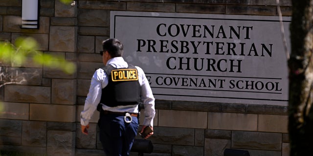 A police officer walks by an entrance to The Covenant School after a shooting in Nashville, Tennessee, on Monday, March 27, 2023. 