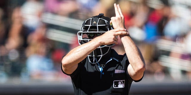 Umpire Matt Brown signals for a pitch clock violation during the spring training game between the Diamondbacks and the Colorado Rockies at Salt River Fields at Talking Stick on March 12, 2023, in Scottsdale, Arizona.