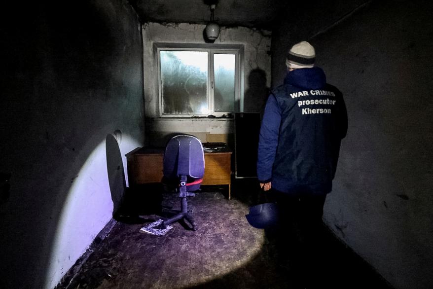 A war crime prosecutor inspects a basement of an office building, where prosecutor's office says 30 people were held for two months during the Russian occupation in Kherson, Ukraine.