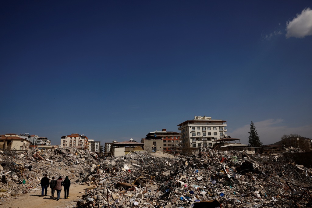 Hasan Arslan and his family walk among what remains of their home, where they were trapped for five days until they were rescued, in the aftermath of a deadly earthquake in Nurdagi, Turkey, on March 4, 2023. 