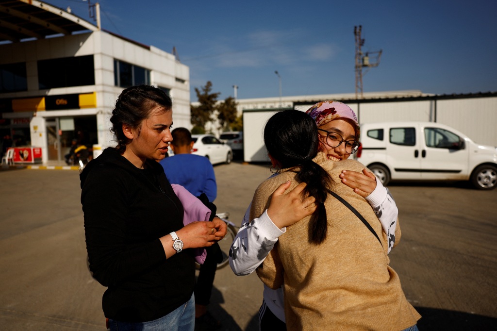 Ikranur Arslan, 13-year-old, hugs a friend who has come to check on her at the petrol station where she lives in a container home with her aunt and grandmother in Nurdagi, Turkey, on March 4, 2023. 