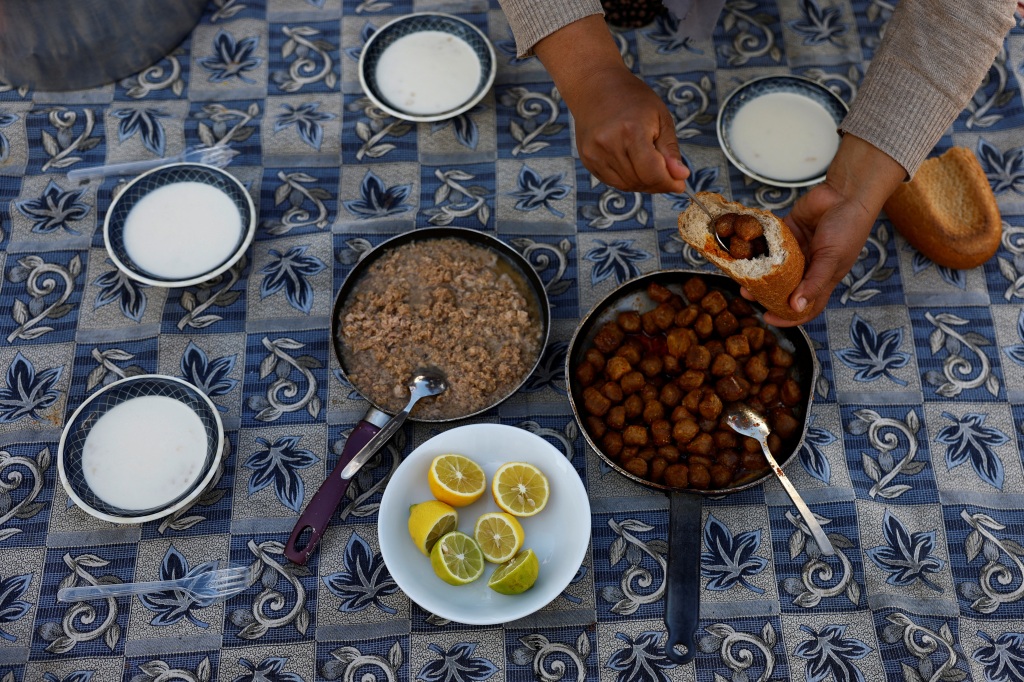 Nurgul Arslan prepares lunch for all family members living in container homes by a petrol station in the aftermath of a deadly earthquake in Nurdagi, on March 4, 2023. 