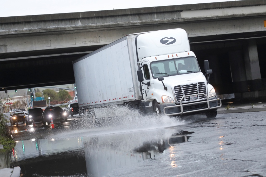 A tractor-trailer drives through a flooded road i Hayward, California on March 10, 2023.