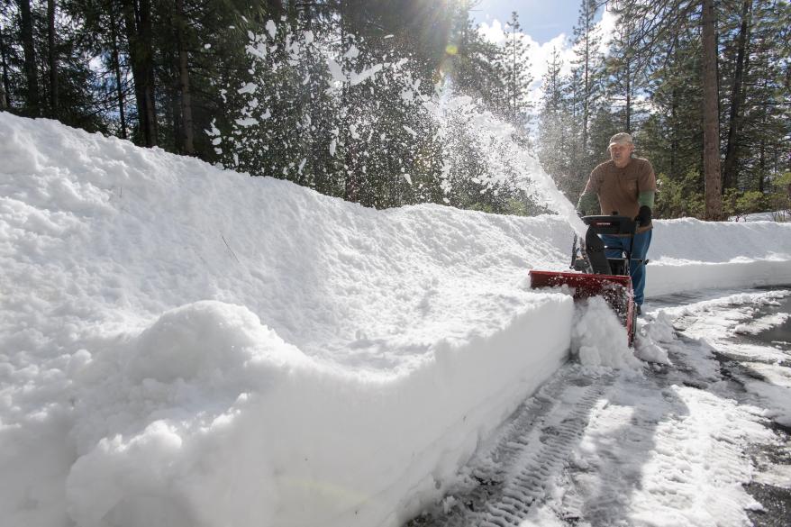 Kim Glasso uses a snow blower to clear his sidewalk around his home in Dutch Flats, Calif.