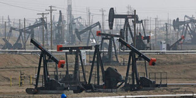 A person walks past pump jacks operating in Bakersfield, California.