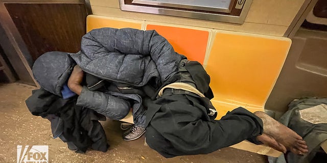 Image shows an individual sleeping in a NYC subway car. 