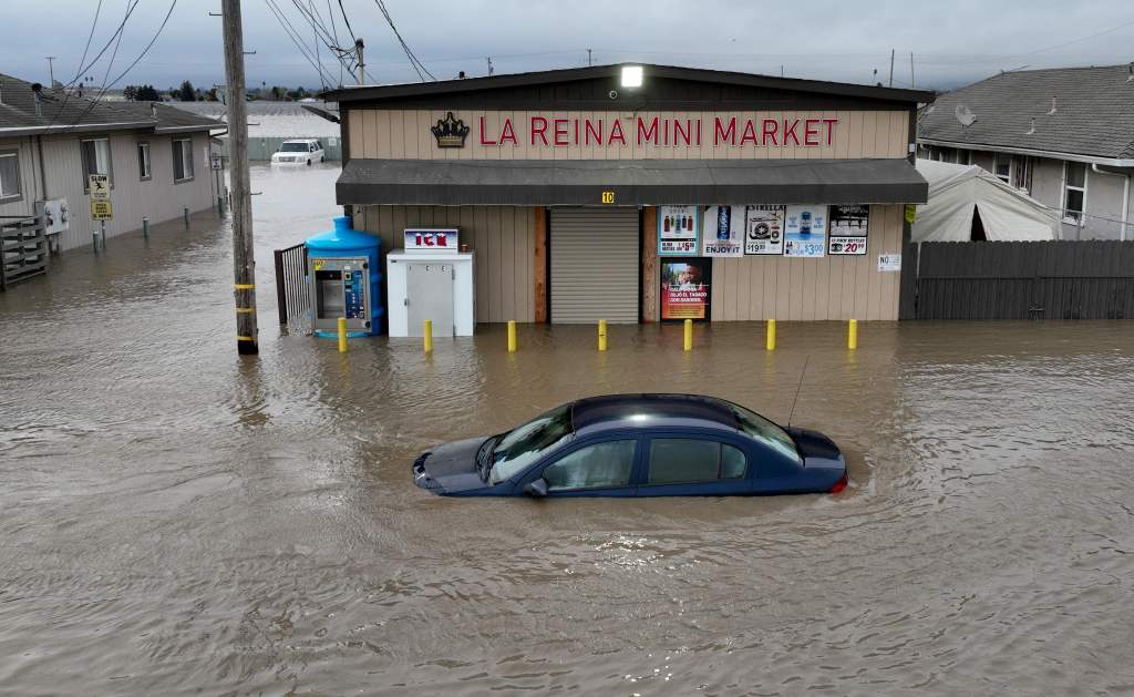 Floodwaters surround a car and market shop in Pajaro, California on March 12, 2023.