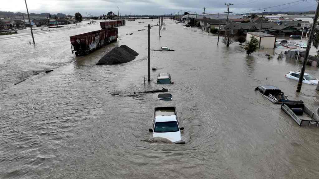 A flooded street with train cars, vehicles and homes after the atmospheric river hit Pajaro, California causing floods and evacuation orders. 