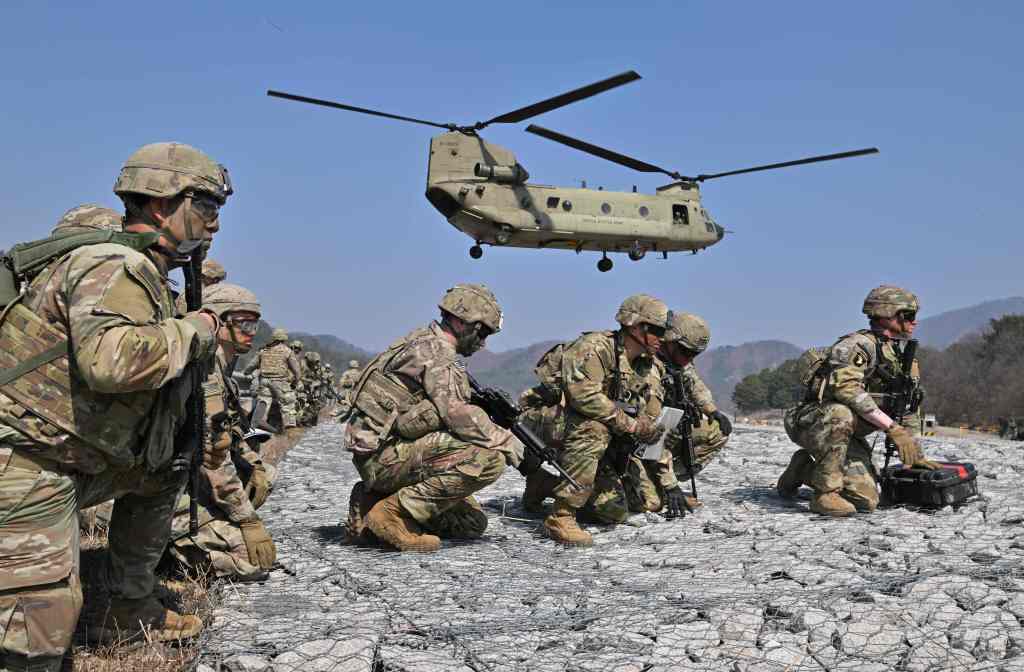 US soldiers take a position as a US Army CH-47 Chinook helicopter prepares to land during a field artillery battalion gun raid drill at a military training field in Pocheon on March 19, 2023.