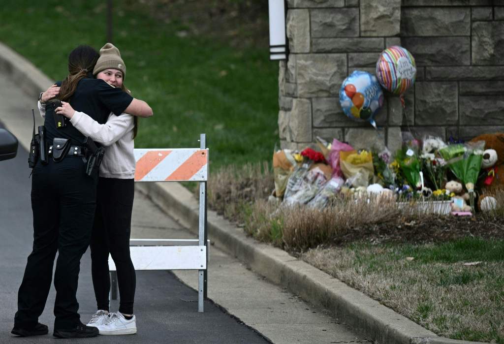 A woman hugs a police officer at the entrance of the Covenant School at the Covenant Presbyterian Church, in Nashville, Tenn., on March 28, 2023.