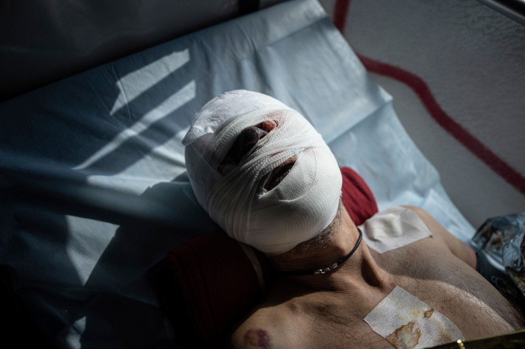 An injured Ukrainian soldier lies on a bed inside a special medical bus during an evacuation by volunteers from the Hospitallers paramedic organisation in the Donetsk region of Ukraine on March 22, 2023.