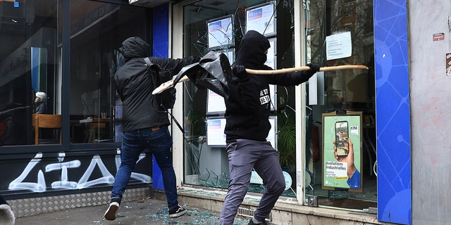 Protesters smash a shop window during a demonstration against the government's plan to raise the retirement age to 64, in Paris March 15, 2023.