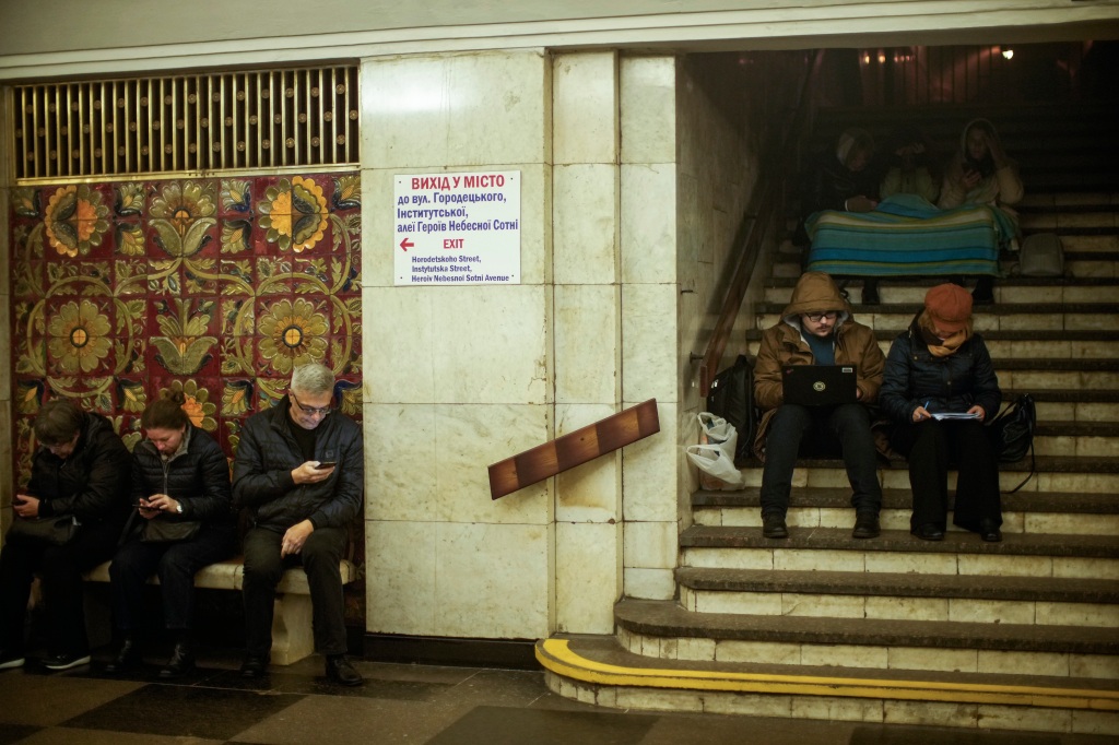 People sit in the subway, using it as a bomb shelter during an air raid alarm, in Kyiv, Ukraine. 