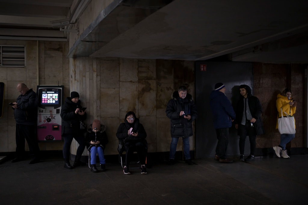 People use their phones while they gather in a metro station during an air raid alarm, in Kyiv, Ukraine.