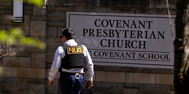 A police officer walks by an entrance to The Covenant School after a shooting in Nashville, Tennessee, on Monday, March 27, 2023. 