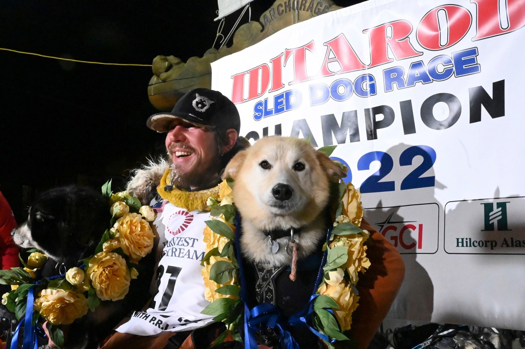 Brent Sass poses for photos with lead dogs Morello, left, and Slater after winning the Iditarod Trail Sled Dog Race in Nome, Alaska, March 15, 2022.