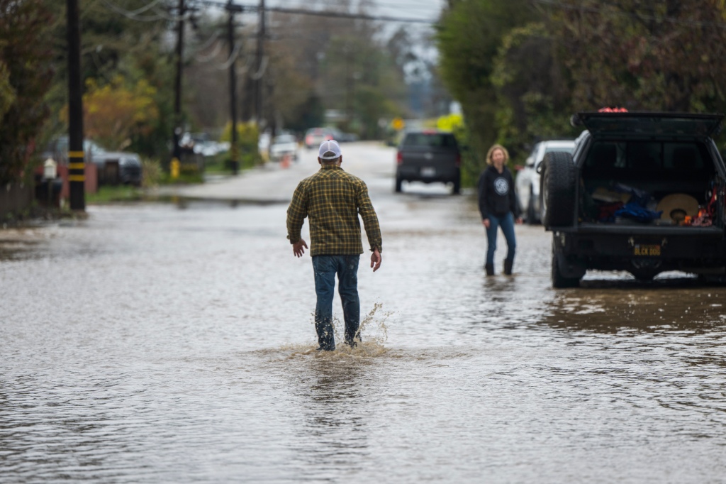 A man walks through floodwaters on College Road in Watsonville, Calif., Friday, March 10, 2023.