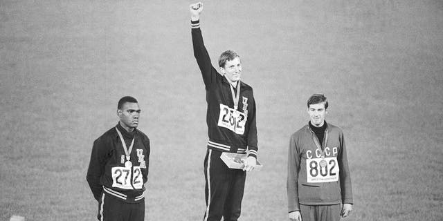 FILE - Gold medal winner Dick Fosbury raises his arm on the victor's podium of the Olympic stadium, Oct. 20, 1968, in Mexico City.