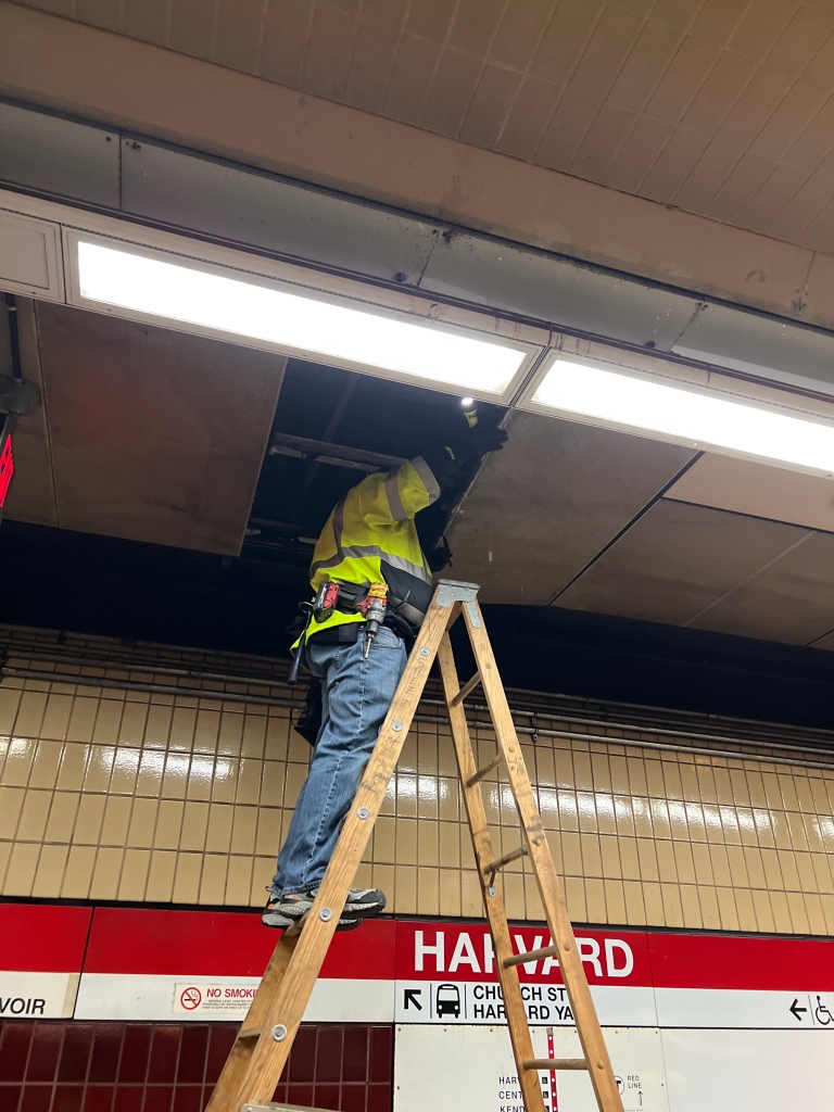 A MBTA worker removes a panel deemed an immediate safety concern. 