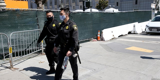 San Francisco County Sheriff's Office deputies pass by a sanctioned and fenced-in homeless encampment across from City Hall in San Francisco, Calif., on May 19, 2020.