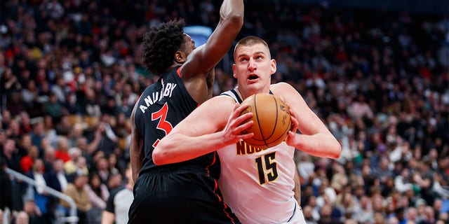 Nikola Jokic of the Denver Nuggets goes to the net around O.G. Anunoby of the Raptors at Scotiabank Arena on March 14, 2023, in Toronto, Canada.