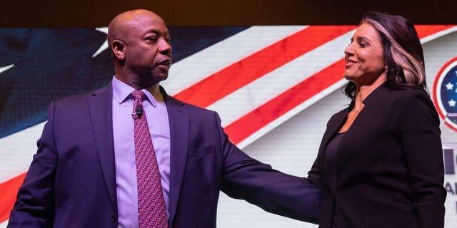 US Senator Tim Scott, R-SC (L) embraces Former US representative Tulsi Gabbard (R) during the Vision 2024 National Conservative Forum at the Charleston Area Convention Center in Charleston, South Carolina, on March 18, 2023.