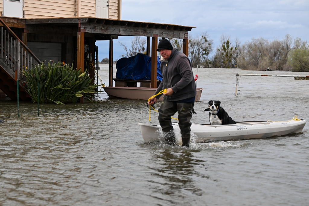 A man takes his dog out with a canoe in flood after levee fails in Manteca of San Joaquin County as atmospheric river storms hit California, on March 21, 2023.