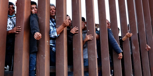 Immigrants wait for soup donated by the Yuma County Abolition group after crossing the border from Mexico on May 23, 2022, in San Luis, Arizona.