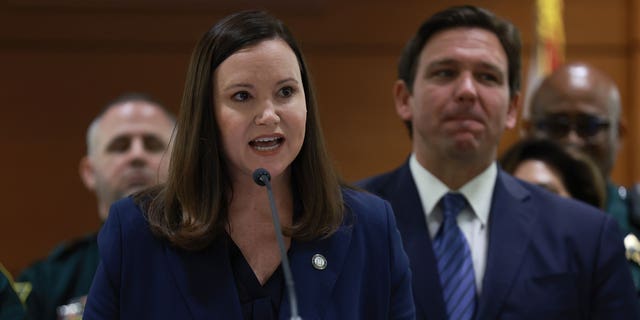 Florida Gov. Ron DeSantis listens as Florida Attorney General Ashley Moody speaks during a press conference at the Broward County Courthouse on August 18, 2022 in Fort Lauderdale, Florida.