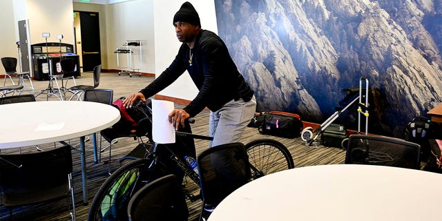 Colorado Buffaloes head football coach Deion Sanders rides a bicycle in to a press conference on National Signing Day on Feb. 1, 2023.