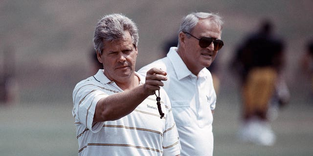 Pittsburgh Steelers Director of Player Personnel Dick Haley, left, looks at a stopwatch as he times players in the 40-yard dash as head coach Chuck Noll looks on during practice at summer training camp at St. Vincent College in July 1991 in Latrobe, Pennsylvania. 