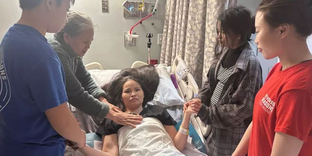 Nhung Truong, seen in a hospital bed surrounded by her mother and children, was left paralyzed after being attacked by a robber in Houston, Texas.