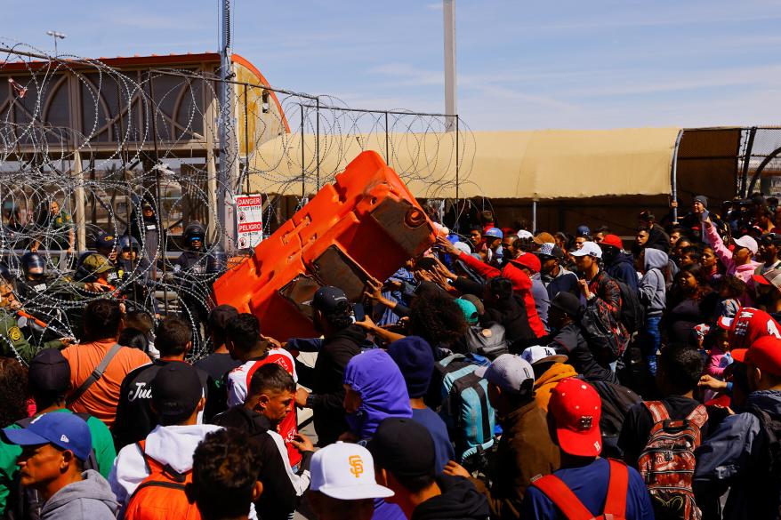 Some migrants tried to break free at one point when they threw an orange, plastic barrier at the US line.