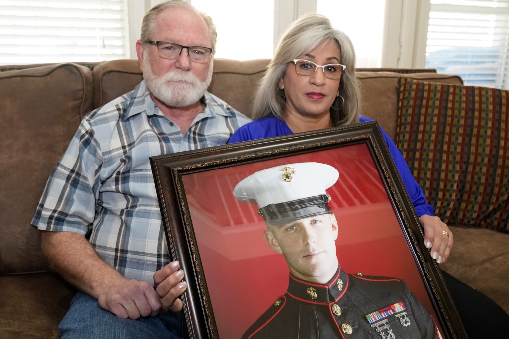 Joey and Paula Reed pose for a photo with a portrait of their son, Marine veteran and Russian prisoner Trevor Reed, at their home in Fort Worth, Texas, Feb. 15, 2022. 