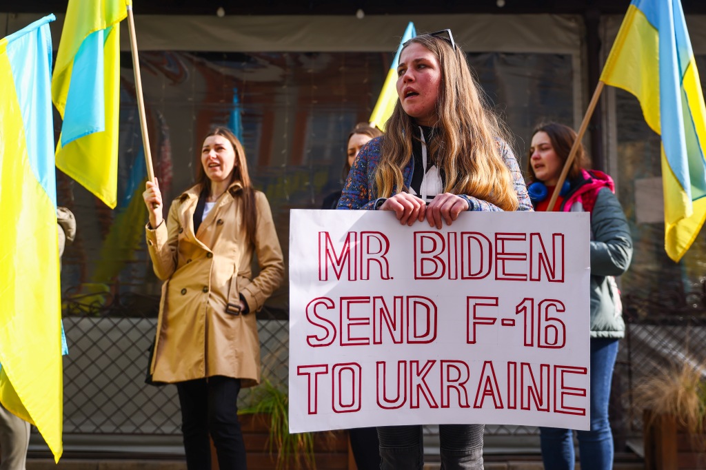 A woman with a sign calls on Biden to send F-16s to Ukraine