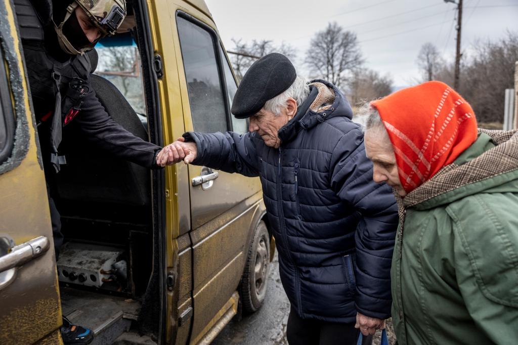 A volunteers assists a local resident onto an evacuation bus on February 28, 2023 from Chasiv Yar, Ukraine.