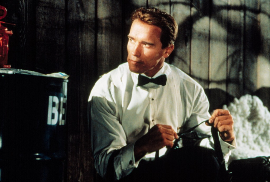 Arnold Schwarzenegger wearing a bow tie crouching in shadows, looking shifty in "True Lies." 