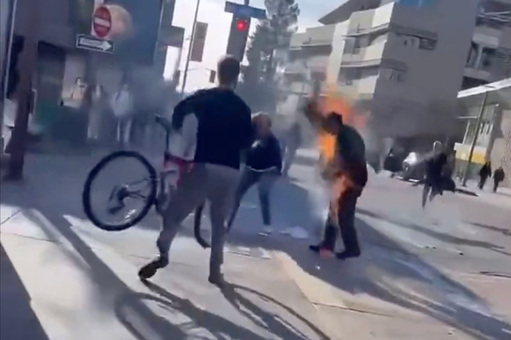 Bystanders try to extinguish the fire and get the man on the ground