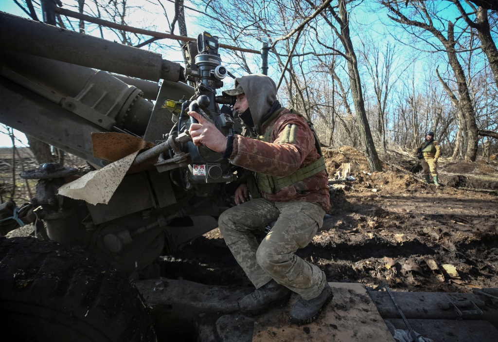 A Ukrainian service member prepares to shoot from a towed howitzer