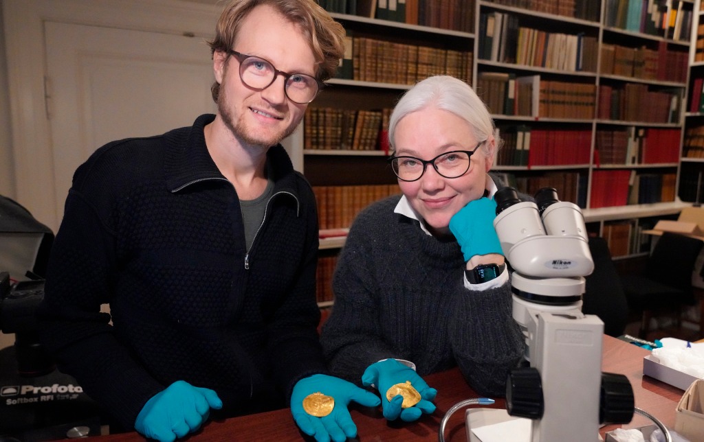 Experts Krister Vasshus, left, and Lisbeth Imer hold golden bracteates unearthed in Vindelev, Denmark in late 2020