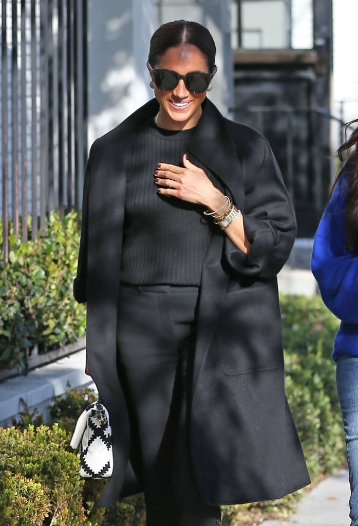 Meghan Markle smiling walking down a street. 