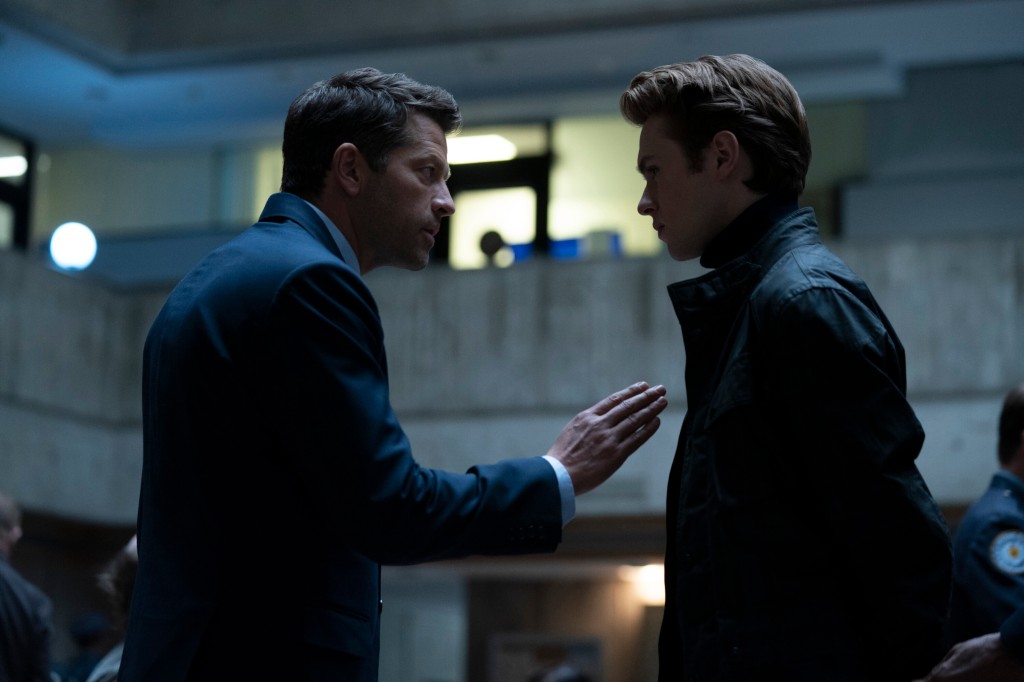 Harvey Dent (Misha Collins) with Turner Hayes (Oscar Morgan) in "Gotham Knights" talking, facing each other looking tense. 