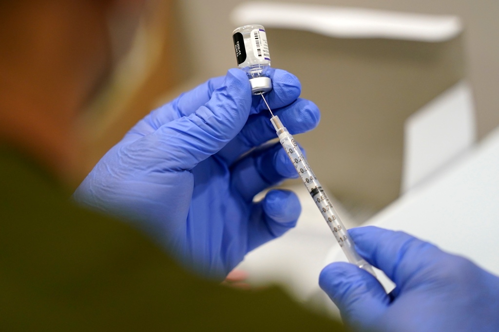 A healthcare worker fills a syringe with the Pfizer COVID-19 vaccine