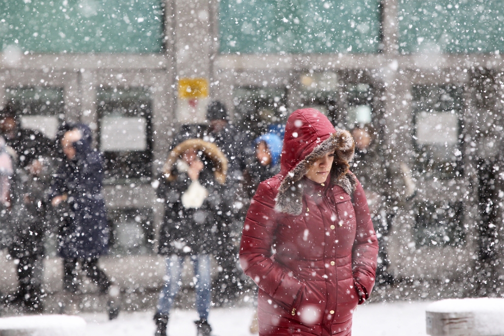 People are pictured walking through a snowfall.