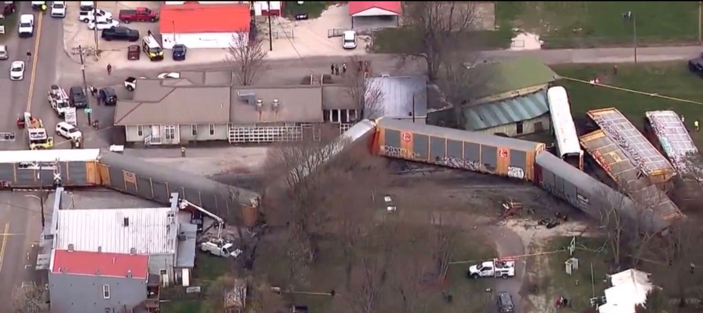 Train lies on the ground near the tracks.