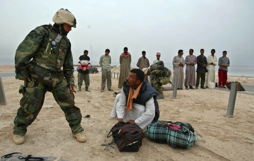 A US Marine checking the bag of a detained Iraqi man in Basra on March 24, 2023.