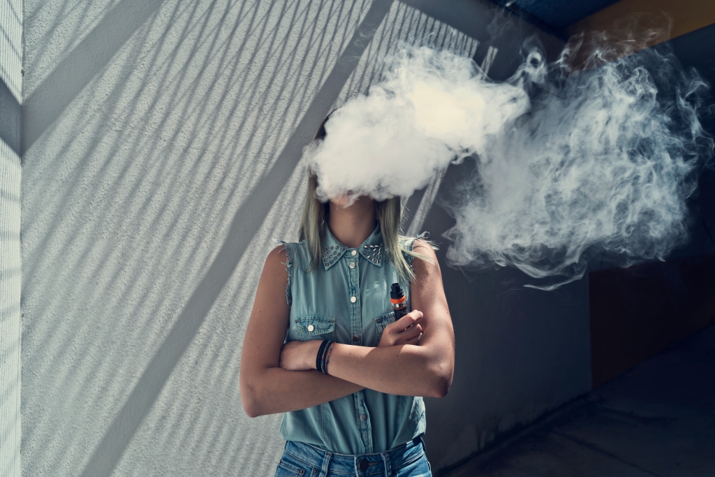 Young woman with her head in a cloud of vapor smoke